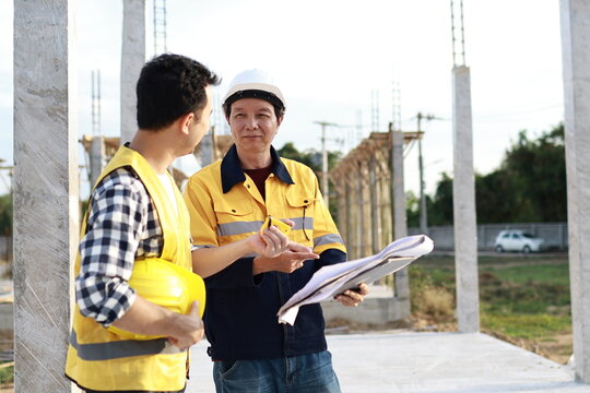 A diverse group of architects, engineers, and business professionals exchange a handshake indoors, symbolizing teamwork, success, and cooperation in a construction industry agreement.