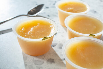 A view of several package cups of apple sauce.