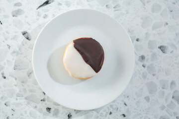 A top down view of a black and white cookie on a plate.