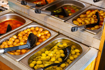 Variety assortment diverse of fresh healthy tasty green and black olives in bowls for sale on market