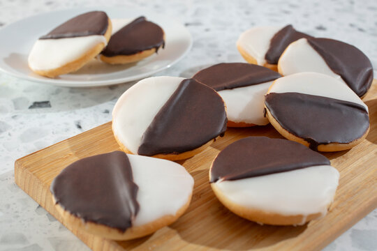 A view of a pile of black and white cookies on a wood board.