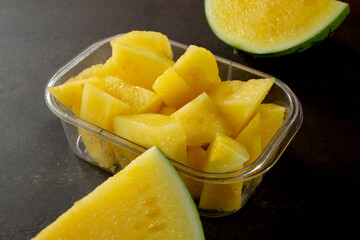 A view of a plastic container of chopped yellow mini seedless watermelon chunks.