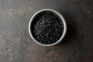 A top down view of a condiment cup of black sea salt.
