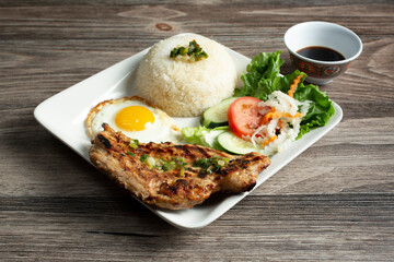 A view of a plate of broken rice, featuring grilled chicken.