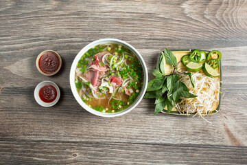 A top down view of a bowl of rare steak pho.