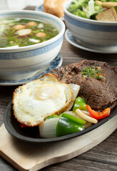 A view of a Vietnamese steak and eggs entree, among other entrees.