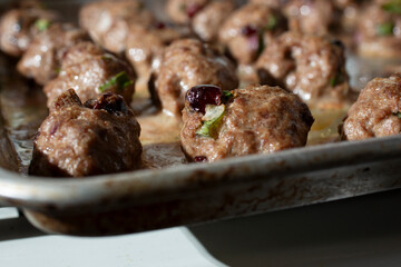 A closeup view of a baking sheet of baked cranberry meatballs.