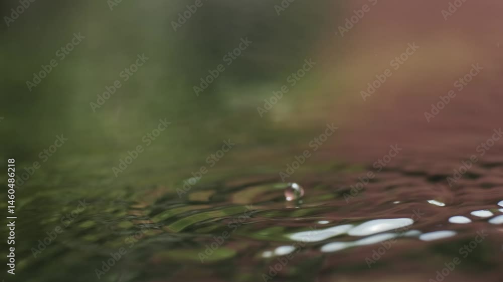 Poster multiple water droplets fall onto a smooth surface, creating expanding concentric ripples that refle