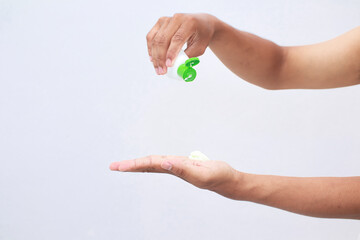 Hand pouring lotion for skin care routine on a clean white surface