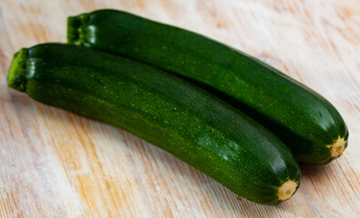 Close-up of fresh green zucchini on wooden desk in kitchen..