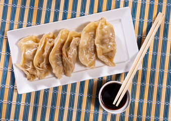 Boiled Yaki Gyoza served in a plate with special sauce and chopsticks