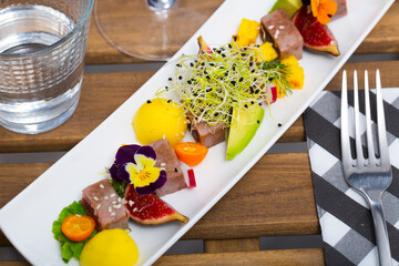 Delicious roasted tuna served with mango, avocado, lime and figs on long plate