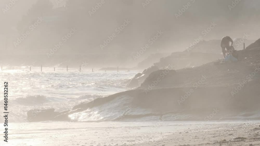 Poster soft sunlight illuminates a couple enjoying the mesmerizing view of ocean waves crashing against a r