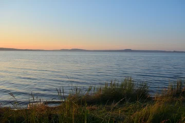 Crédence de cuisine Beige Reeds on the shore of a large lake surrounded by hills on a summer evening at sunset.  © Алексей Желтухин
