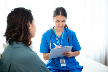 Caregiver sitting on sofa checkup and diagnostic with woman patient about health in living room at home, caretaker sitting on couch explaining and examining woman, insurance and medical.
