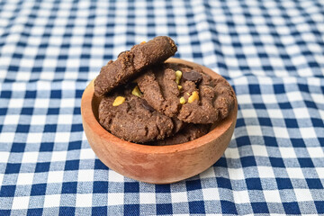 Close up view of cookies with peanut and chocolate chips in little wooden bowl isolated on napkin background. Freshly Baked Homemade. perfect for bakery advertisements and dessert menus.