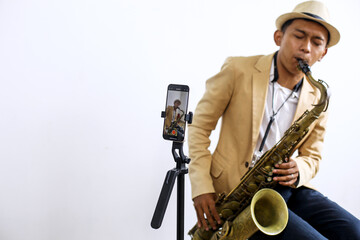 Fototapeta premium Portrait Of Saxophonist Playing A Music While Recording Vlog Using Smartphone At Music Studio