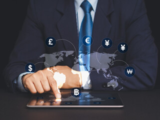 Businessman using tablet with global currency symbols and world map for financial planning.