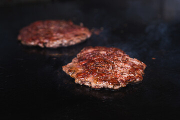 Close-up of grilled ground beef patties cooking for classic cheeseburger preparation.