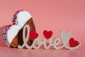 Wooden word LOVE symbol holiday celebration Valentine's Day Heart shaped white chocolate croissant on pink background with copy space. Puff pastry new trendy sweet dessert bakery. Creamy dough
