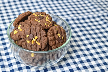 Close up view of cookies with peanut and chocolate chips in glass bowl isolated on napkin background. Freshly Baked Homemade. perfect for bakery advertisements and dessert menus. Copy space, empty.