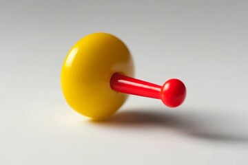 Yellow disc with red rod toy.  A small, brightly colored, spinning top