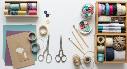 Fototapeta premium Overhead shot of craft supplies including ribbons, buttons, scissors, and paint brushes on white surface