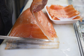 Slicing fresh salmon fillets at a busy fish market