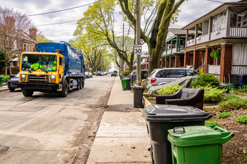 garbage truck on the street in an older residential neighbourhood with bins out for pick up shot in...
