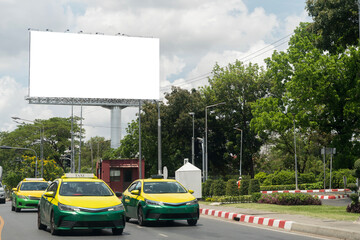 Blank digital billboard on the side of a taxi stand, with parked taxis waiting in line and drivers...