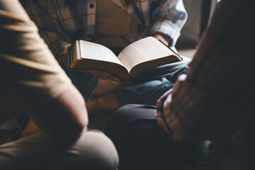 Close up group christians hands pray to God with spiritual faith on holy bible in catholic church....