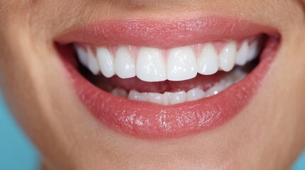 Close-up of a woman with a bright smile, healthy white teeth, plain blue background indoors, cropped shot.