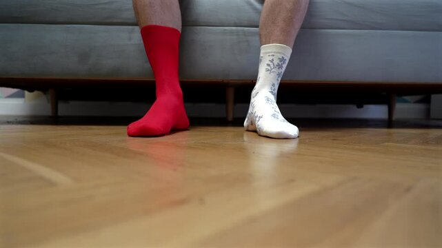Different socks in legs. Mismatched multicolored socks on feet man. Men's legs in Different socks as symbol of down syndrome. Down syndrome awareness concept. Wear Mismatched Socks. Disabled person.
