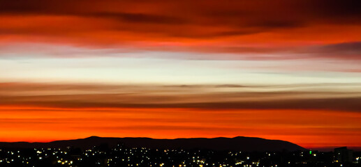 Sunrise in Australia, with city lights in front of a dark mountain range