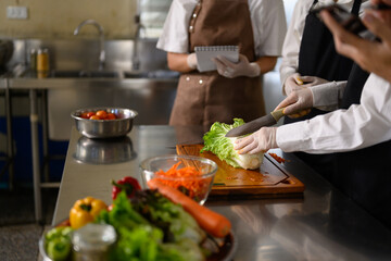 Chef guiding students in vegetable preparation during a hands-on culinary class