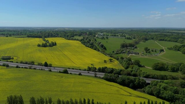 Aerial drone rural green agriculture landscape rapeseed England UK Spring summer Sunshine evening motorway roads countryside 