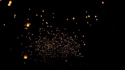 Hundreds of lanterns illuminate the night sky during Yi Peng celebration in Chiang Mai, creating a magical, glowing scene.