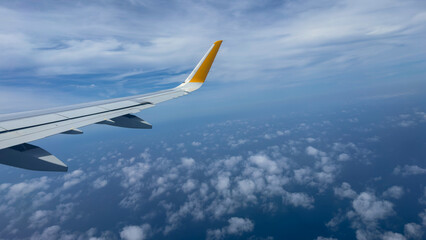 Wing of airplane flying through dynamic cloudy sky. Room for text makes it suitable for travel ads, lifestyle content, or aviation themes.