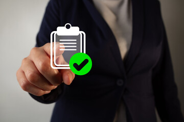 Businesswoman points to an icon of a paper clip with a checkmark in a circle