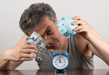 Conceptual story about poverty with a grey-haired middle-aged man, 100 dollars bill, alarm clock...