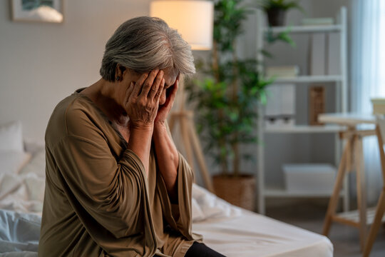 Asian senior elderly depressed woman sitting alone in bedroom at home.  - Powered by Adobe