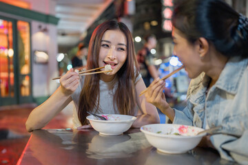 Asian beautiful women traveler eating street food outdoors in the city.