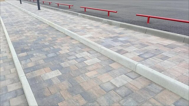 A red metal fence near a staircase made of paving stones on the street. The sidewalk is fenced. Construction of roads and sidewalks in the city.