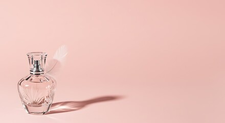 Elegant clear glass perfume bottle rests on a soft pink surface with a feather accent softly draped