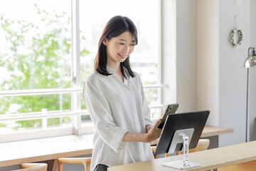 ホテルで受付をする若い女性　タブレット　セルフチェックイン
