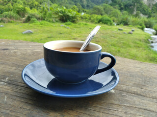 a cup of coffee with milk on the table with a spoon in the photo from the top angle