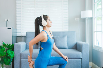 Young Asian woman practices yoga by stretching her back on a yoga mat in the living room at home....