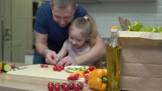 Father and daughter joyfully preparing healthy salad together at home