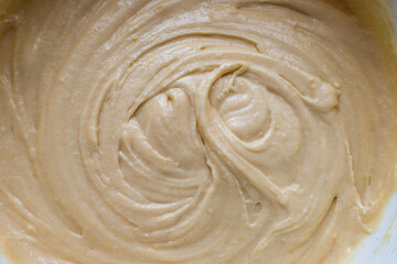 Bowl of dough with a swirl pattern. Kneading the raw dough of a light color. View from above. Homemade baking and confectionery from wheat flour