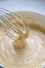 Kneading the raw dough with a metal whisk in a white bowl. Homemade baking and confectionery from wheat flour. Making bread and muffins